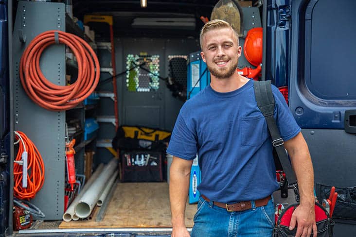 HVAC Career Opportunities HVAC technician smiling standing next to service vehicle filled with tools