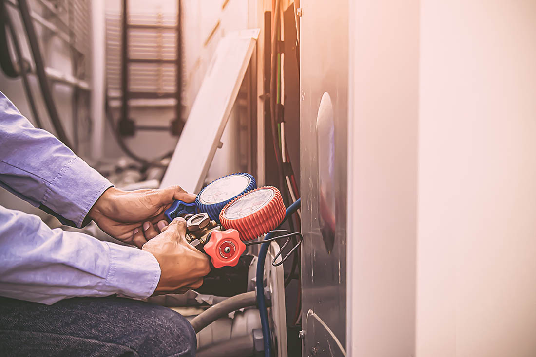 Air repairman technician using manifold gauge is measuring equip HVAC technician performing commercial HVAC service