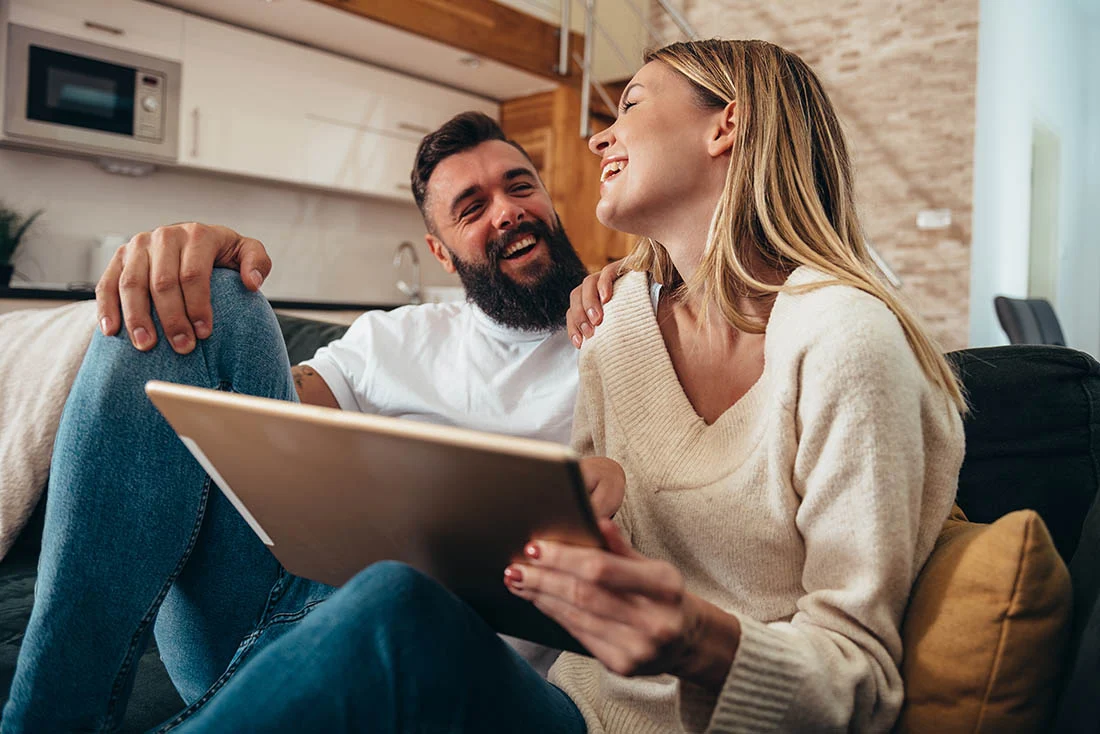 Couple sitting with their tablet laughing