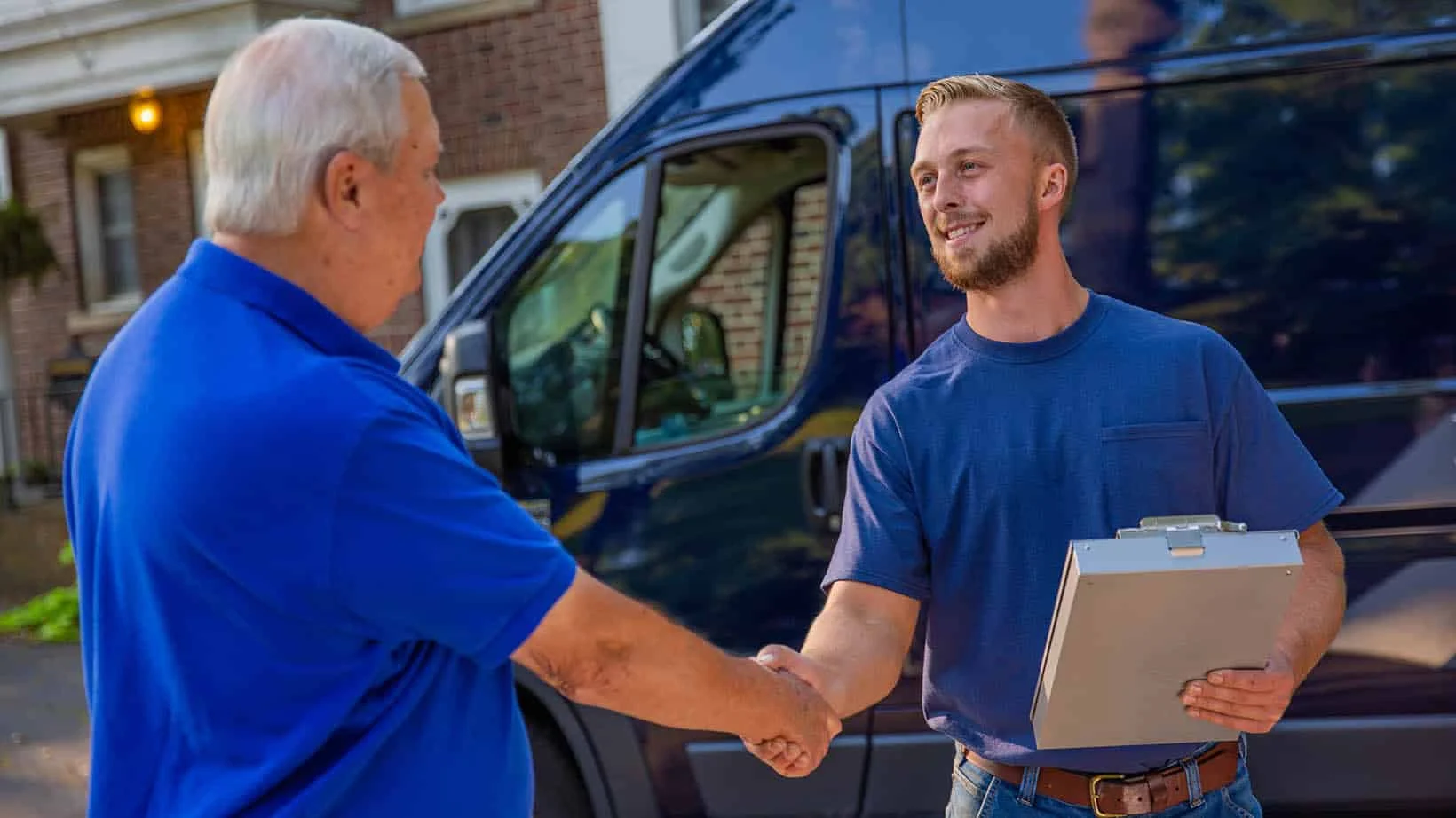 HVAC technician shaking the hand of a homeowner in front driveway