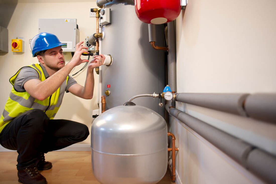 waterHeaters-WaterHeaterMaintenance-Supporting-1100×734 Service technician performing maintenance service on a tank water heater