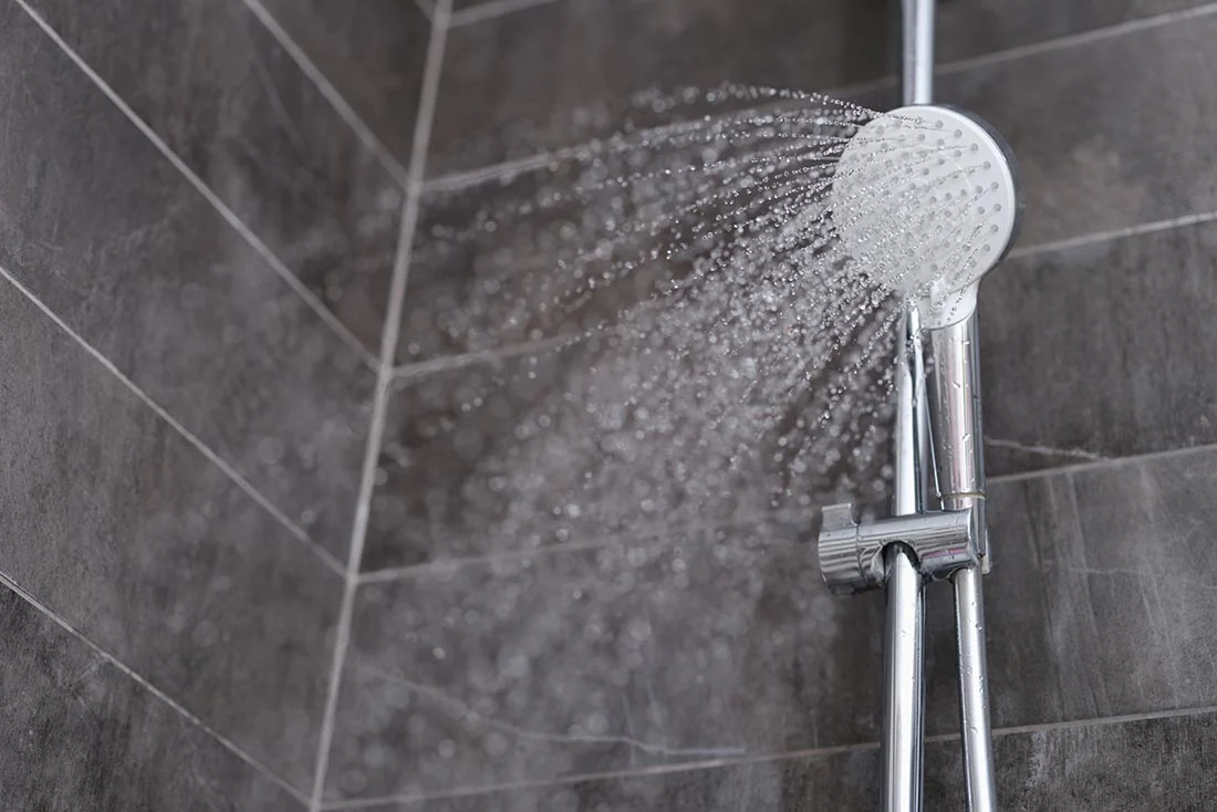 Trickles of water flowing from shower head in bathroom closeup waterHeaters TanklessWaterHeaters Supporting 1100x734 1